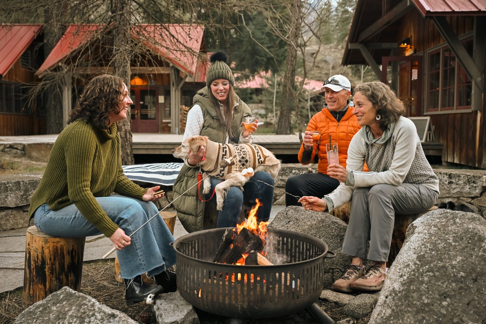 Guests and their dog gathering around a firepit at Sleeping Lady Mountain Resort