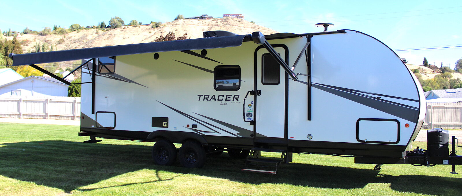 Travel trailer with its awning out parked on grass, available from Wenatchee RV Rental