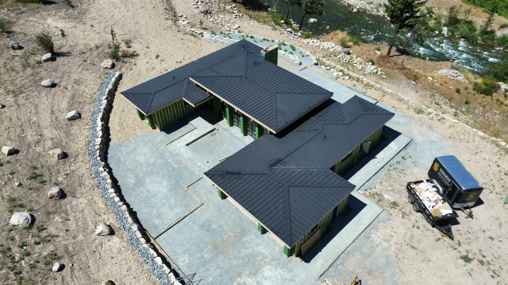 Aerial view of a completed standing seam metal roof on a new build, with Empire's dump trailer on site